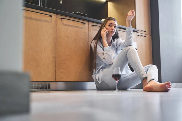 Serieus meisje met een gadget zitten op de vloer — Stockfoto