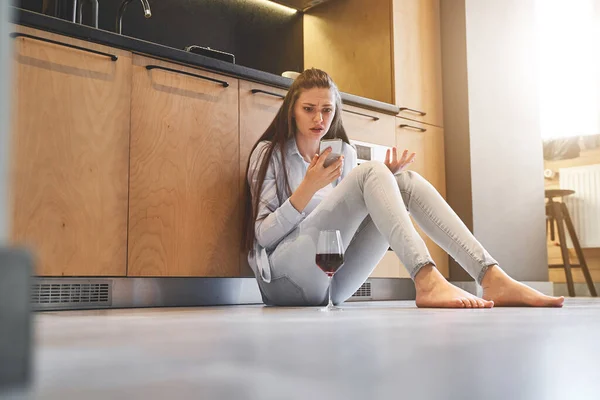 Fată perplexată care o ține pe podeaua bucătăriei — Fotografie, imagine de stoc