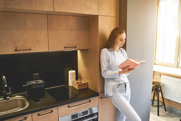 Serieuze blanke huisvrouw op zoek naar een boek — Stockfoto