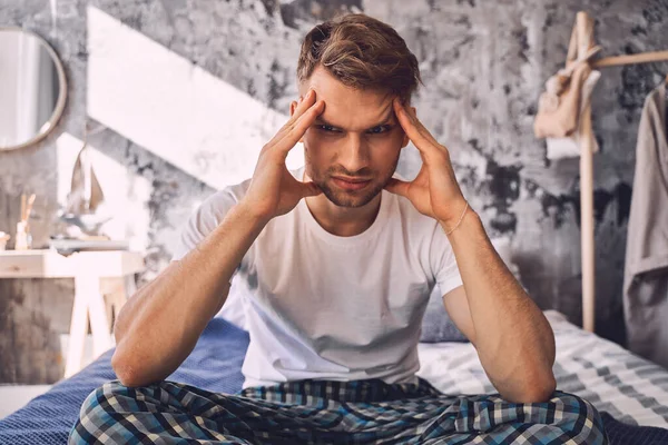 Serious young male touching his head during thinking — Stock Photo, Image