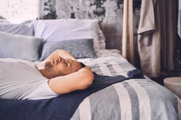 Оброблений молодий чоловік лежить на ліжку — стокове фото