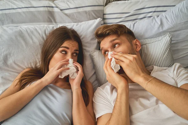 Homem e mulher doentes limpando seus narizes — Fotografia de Stock