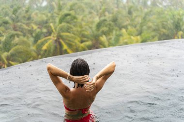 Dışarıda duran kırmızı bikinili, siyah saçlı kadın.