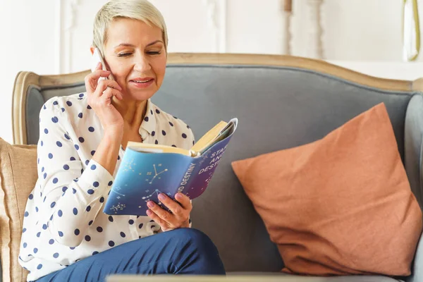 Zufriedene ältere Dame mit einem Astrologiebuch — Stockfoto