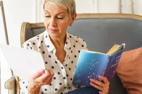 Приємна блондинка тримає книгу астрології — стокове фото
