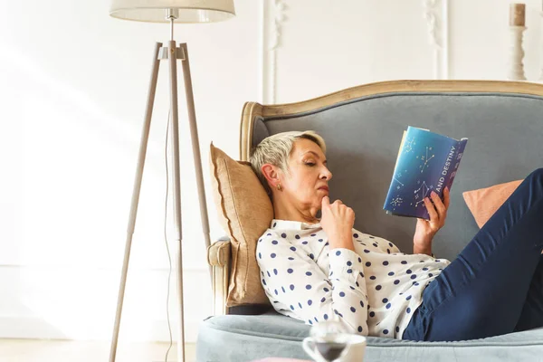 Mulher loira focada lendo um livro de astrologia — Fotografia de Stock