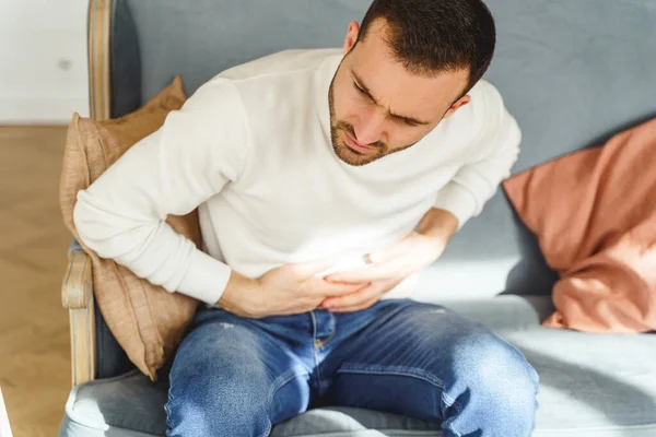 Ung man vrider sig i magen smärta — Stockfoto