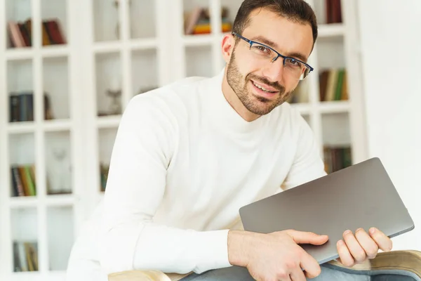 Elinde dizüstü bilgisayarla gülümseyen genç bir ofis çalışanı — Stok fotoğraf