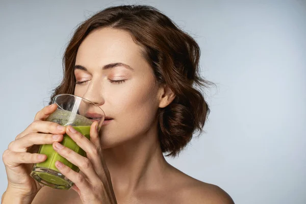 Ung vacker kvinna som tar ett glas grönsakssmoothie — Stockfoto