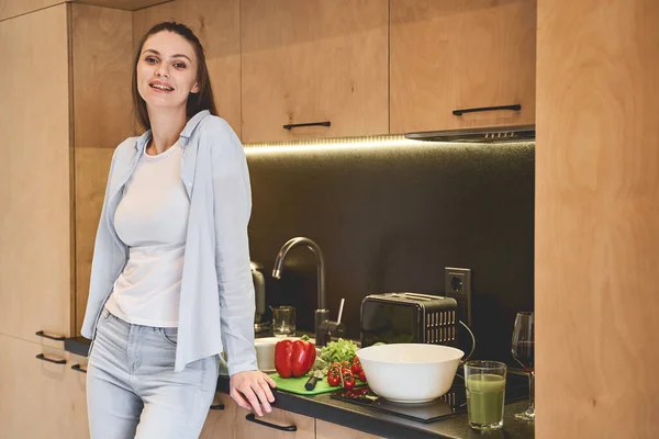 Радостная привлекательная домохозяйка, стоящая на кухне — стоковое фото