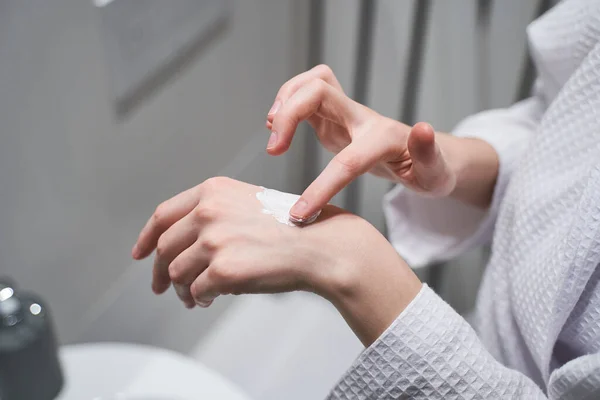 Mujer frotando una crema hidratante en su piel —  Fotos de Stock