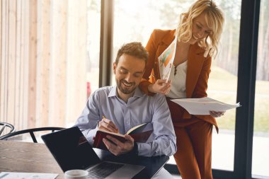 Erkek meslektaşlarının omzuna yaslanan eskizlerle bir kadın.
