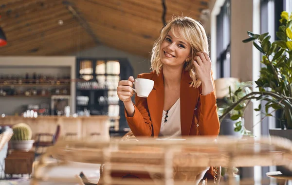 Smiling beautiful stylish blonde female sitting indoors — Stock Photo, Image