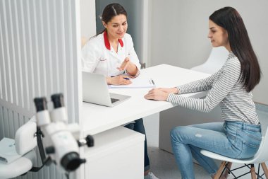 Nazik genç esmer kadın doktorunu ziyaret ediyor.