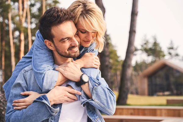 Smiling young man enjoying his girlfriends hugs — Stock Photo, Image