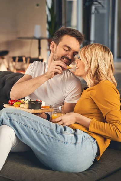 Gelukkige getrouwde mensen eten samen op de bank — Stockfoto