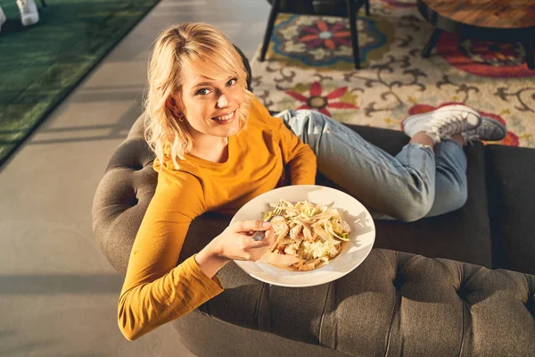 Mujer agradable disfrutando de su almuerzo en el sofá — Foto de Stock