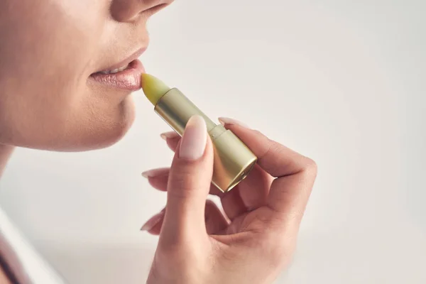 Mujer joven usando un humectante labial natural — Foto de Stock