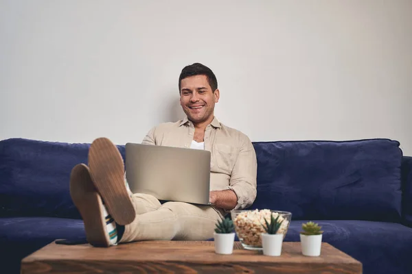 Homme souriant avec un ordinateur portable sur les genoux — Photo