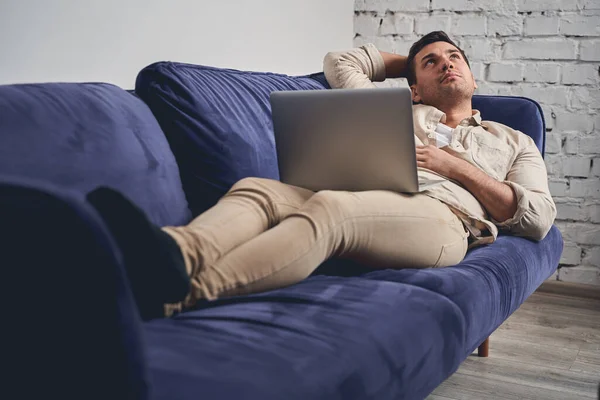 Pensivo homem de cabelos curtos descansando no sofá — Fotografia de Stock