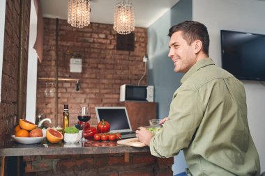 Gülümseyen orta yaşlı beyaz adam kendine yemek yapıyor.