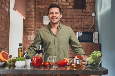 Mutfakta kameraya gülümseyen bir erkek.