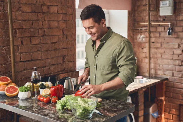 Glada mörkhåriga hane förbereder en hälsosam sallad — Stockfoto