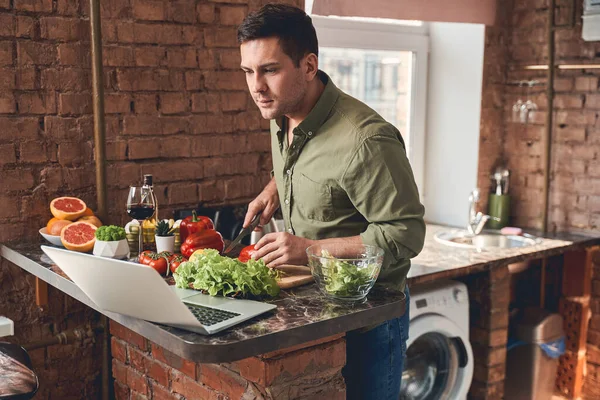 Sérieux beau mâle suivant une recette en ligne — Photo