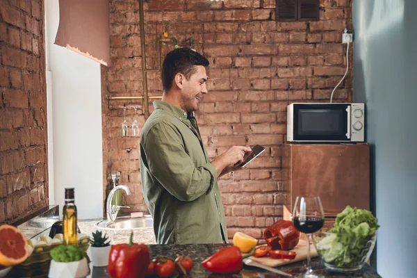 Leende manlig kock tittar på sin gadget — Stockfoto