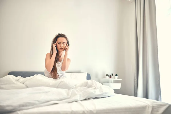 Blanke dame met hoofdpijn zittend op zacht bed — Stockfoto