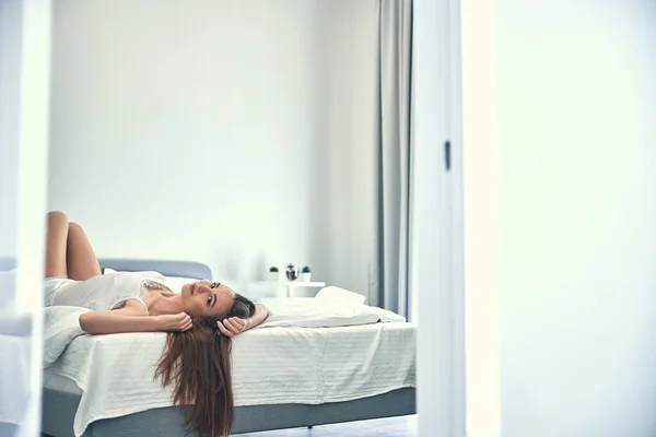 Kaukaska dziewczyna leżące na miękkim świetle łóżko w przytulnej sypialni — Zdjęcie stockowe