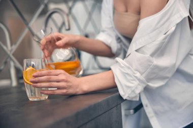 Beyaz kadın evde cama limonata döküyor.