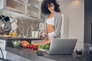 Kadın aşçı mutfakta dizüstü bilgisayarını kullanıyor.