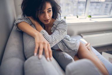 Güzel siyah saçlı kadın kanepede dinleniyor.