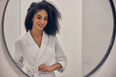 Kız aynada kendine gülümsüyor.