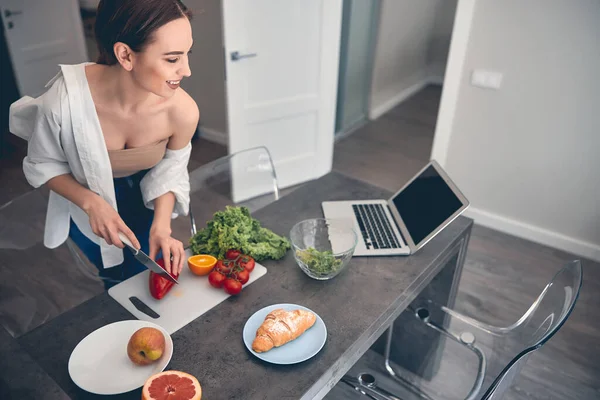 Mujer joven caucásica cortando verduras a bordo en casa — Foto de Stock