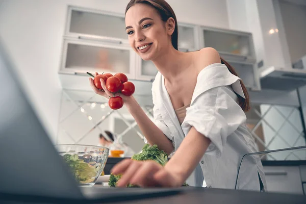 Caucásico positivo señora cocina con verduras en la cocina —  Fotos de Stock