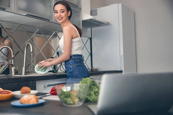 Blanke positieve dame afwassen in de keuken — Stockfoto