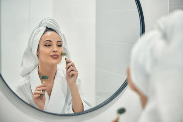 Sorriso mulher atraente olhando para o espelho em seu banheiro luz — Fotografia de Stock