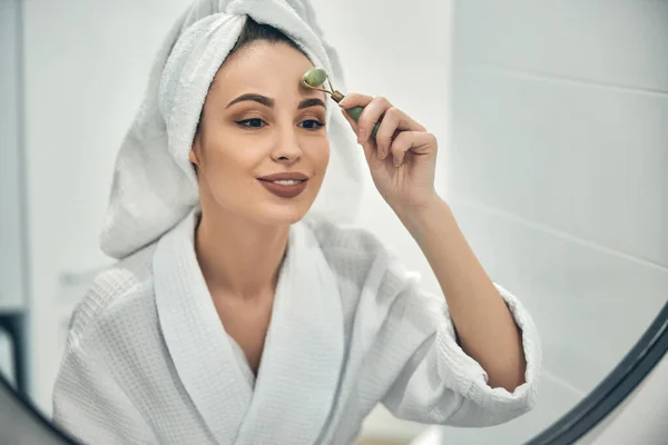 Caucasian lady doing face massage opposite mirror — Stock Photo, Image