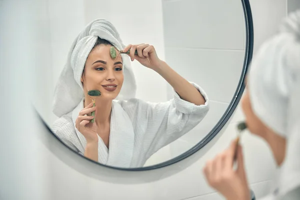Caucásico sonriente dama haciendo masaje facial en baño —  Fotos de Stock