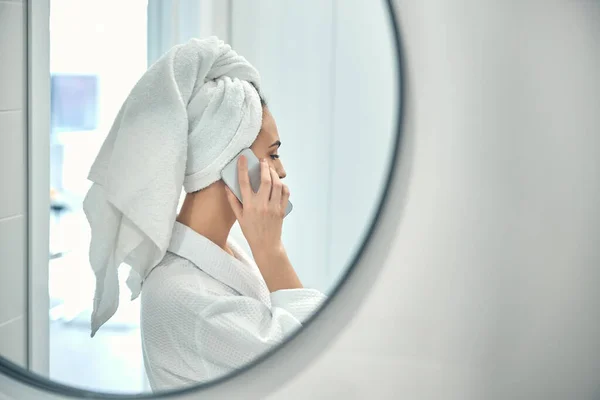 Vit kvinna med vit handduk på huvudet pratar i telefon — Stockfoto