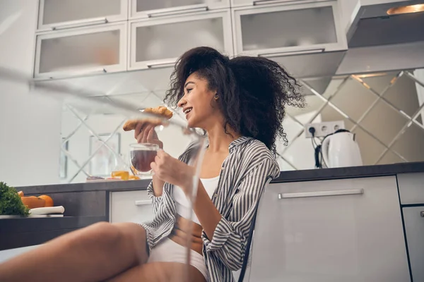 Mujer con un croissant y una bebida caliente — Foto de Stock