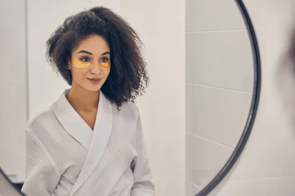 Flicka med under ögonen gel kuddar i ett badrum — Stockfoto