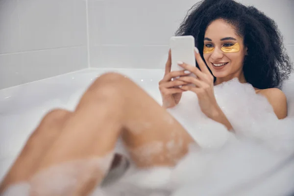 Menina usando um smartphone em uma banheira — Fotografia de Stock