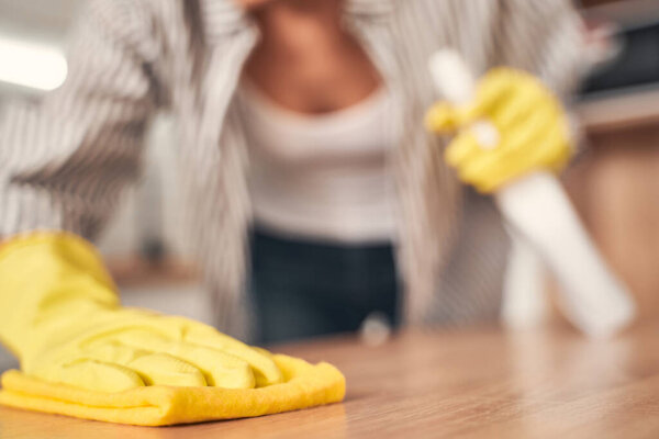 Закрыть женскую руку, которая вытирает пыль
