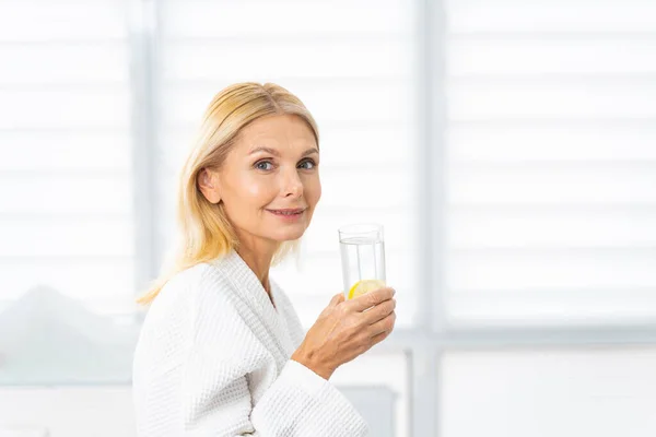 Atractiva mujer madura con un vaso de bebida —  Fotos de Stock