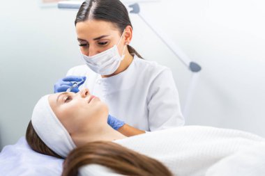 Hastanın alnına deri doldurucu enjekte ediliyor.