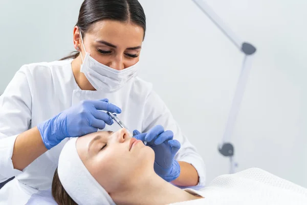 Dermatólogo inyectando un relleno de mejillas a una mujer — Foto de Stock