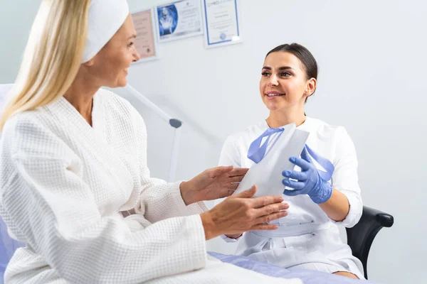 Patient with a paper bag looking at her dermatologist — Stock Photo, Image